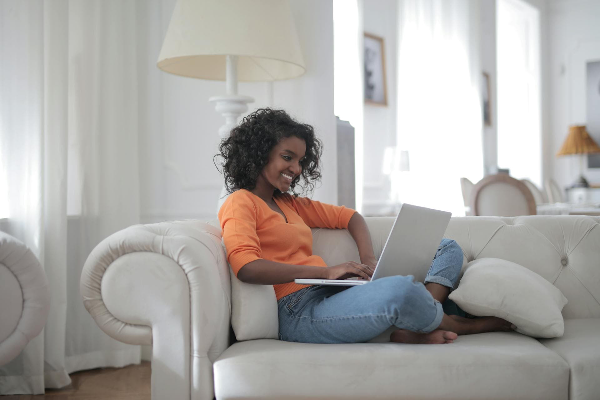 A tutor working from a laptop on a sofa at home