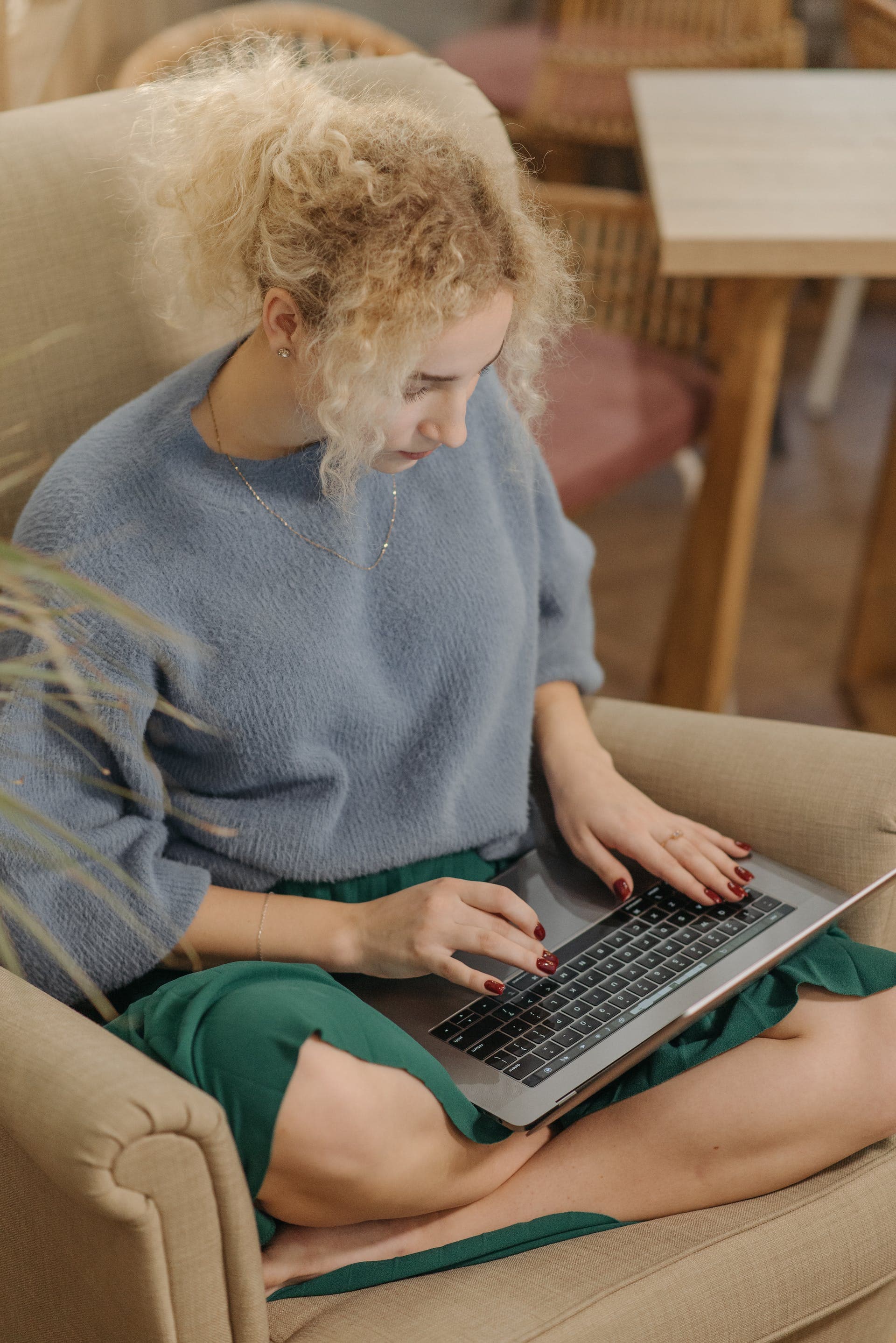 A tutor typing on a laptop in an armchair
